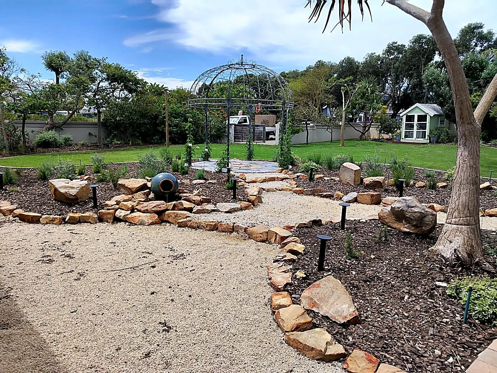 A winding gravel path edged with rocks between new planting
