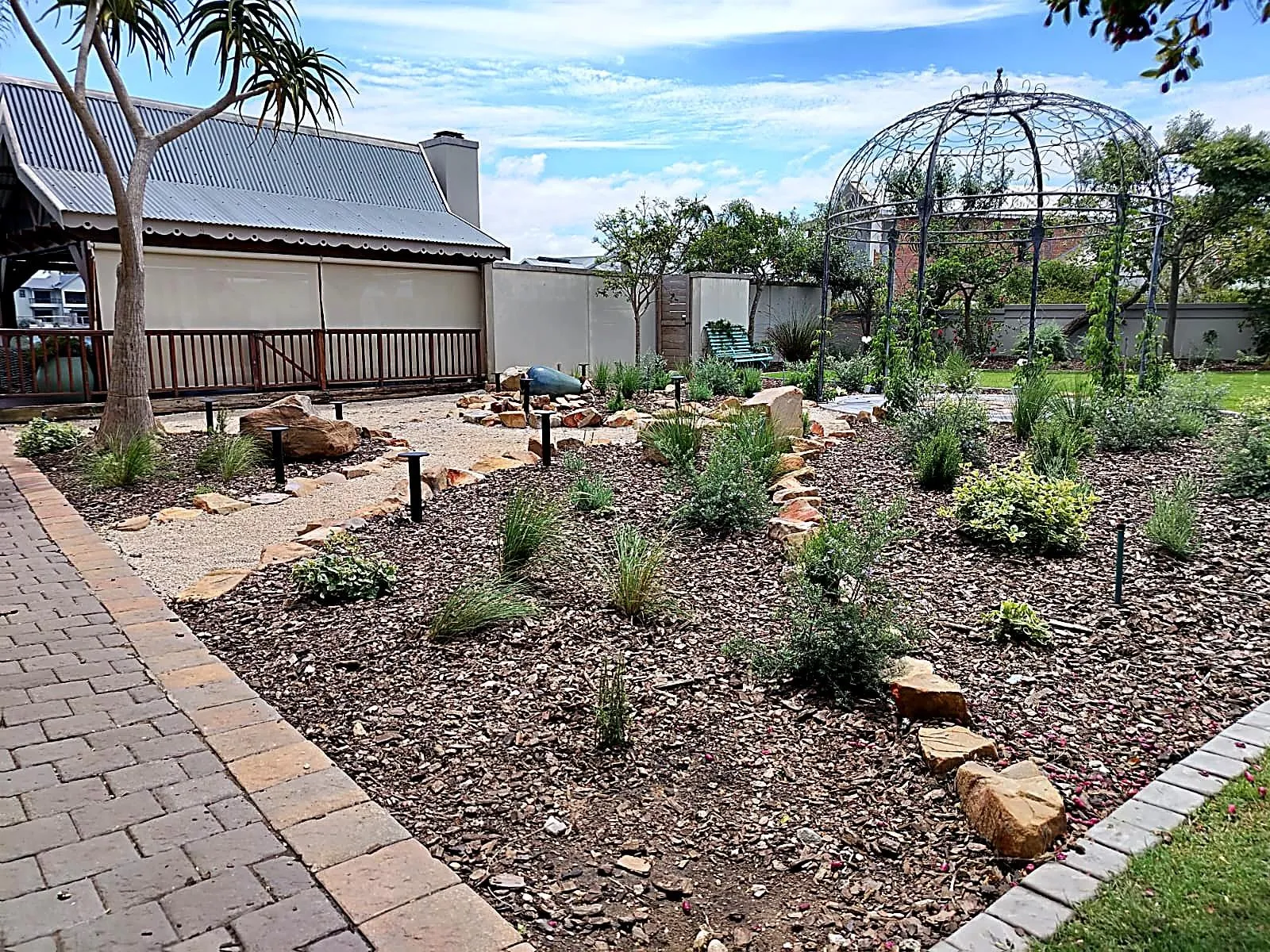 Planted beds along a brick path, with the gazebo behind