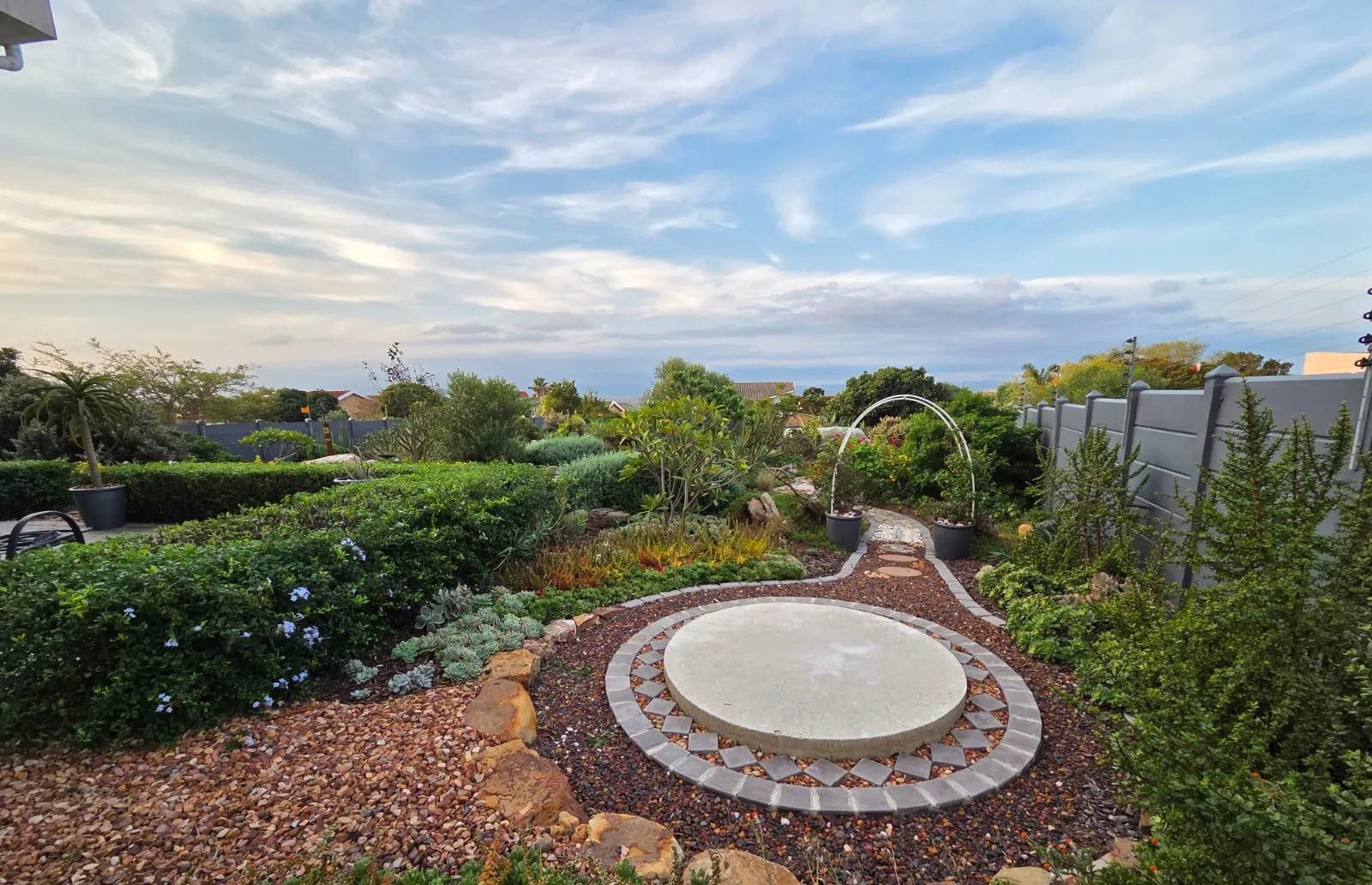 A round paved feature edged with brick, surrounded by indigenous planting and gravel