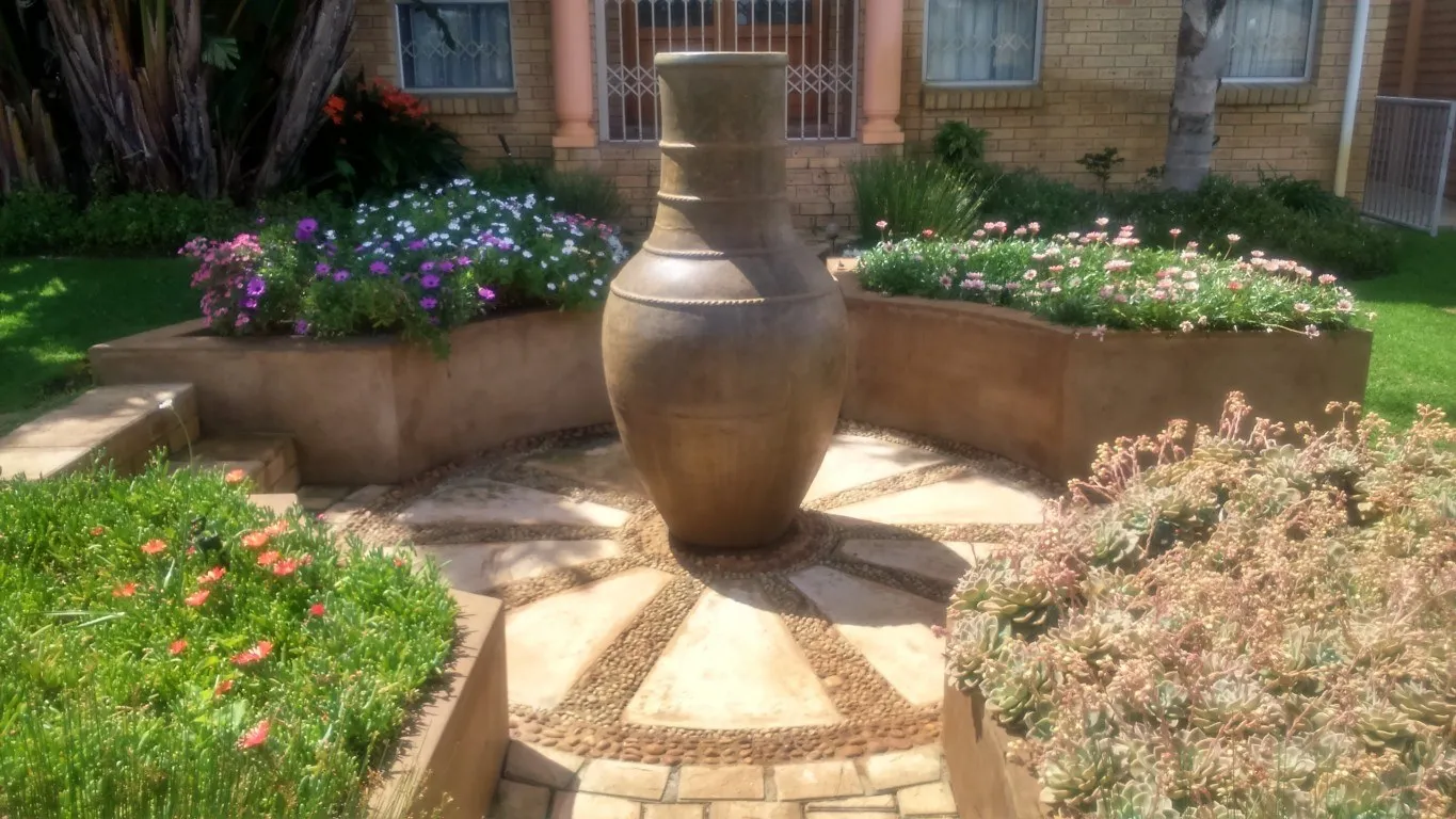 A large garden urn surrounded by colourful flowering plants